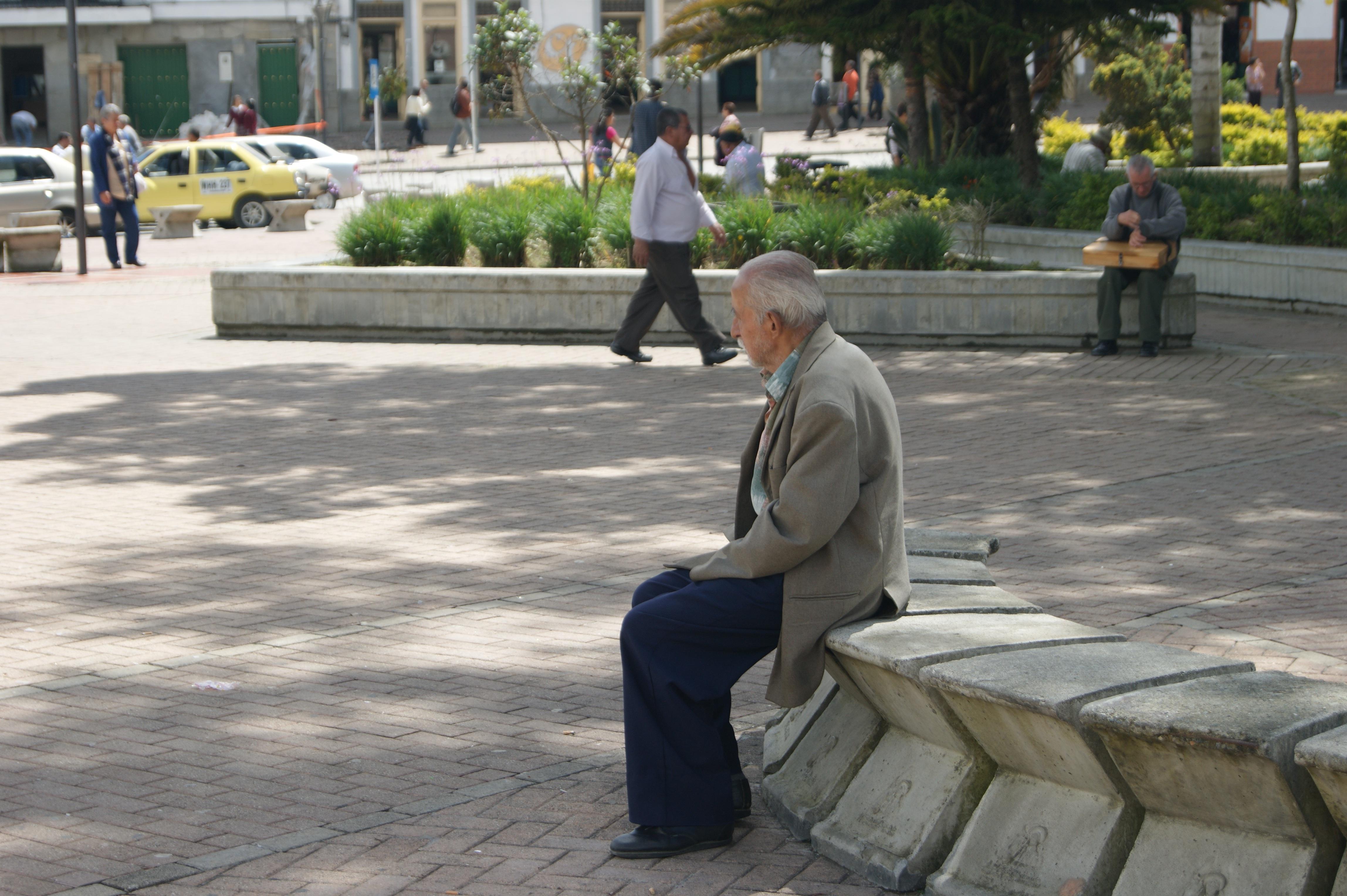 Persona adulta mayor sentada en una plaza