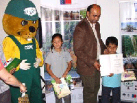 Julio Torres, Secretario Ejecutivo del Colegio de Ingenieros Forestales y académico de la Facultad hace entrega de menciones honrosas a los alumnos de enseñanza básica.
