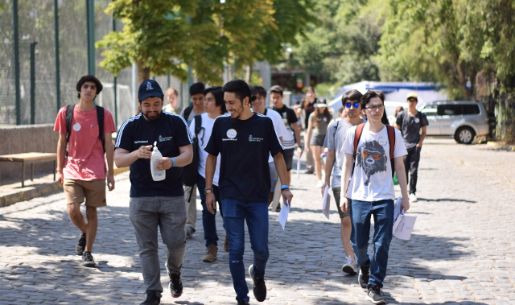 Grupo de estudiantes junto a monitores, caminando al aire libre, al interior de la Facultad de Economía y Negocios de la Universidad de Chile
