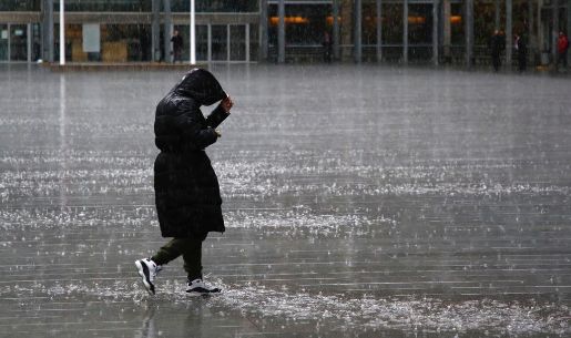 La imagen muestra a una persona caminando bajo la lluvia.
