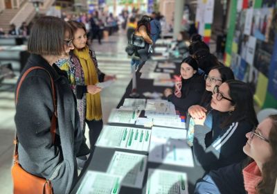 Rectora Rosa Devés y directora Leonor Armanet conversando con estudiantes monitoras en un stand