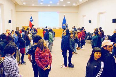 Al interior de la sala Eloísa Díaz, de Casa Central de la U. de Chile, se ve a jóvenes de pie, en parejas, espalda con espalda, en una actividad de taller.