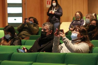 Asistentes con mascarilla, sentados en el salón de honor de FEN, tomando atención y fotografías con sus celulares