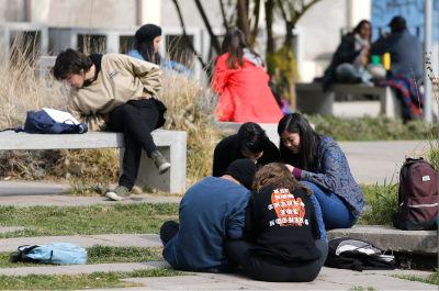 Grupos de estudiantes sentadas y sentados en los patios del campus Juan Gómez Millas