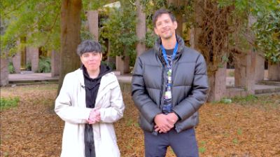 La profesora Carolina Espinoza y el profesor Boris Marinkovic de la U. de Chile, posando frente a la cámara, con un fondo de árboles y hojas otoñales