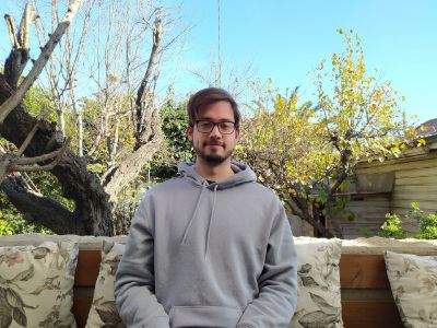 Leopoldo Cárdenas, tutor y estudiante de pre y postgrado de la U. de Chile. Sentado en el exterior, con árboles detrás