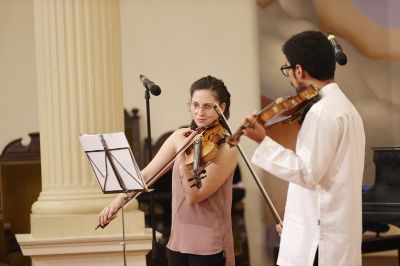 Yanara Quintana y Nicolás González tocando el violín en el Salón de Honor