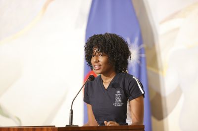 Plano medio corto de la estudiante Nairobis Almonord, hablando en la testera del Salón de Honor