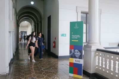 Pasillo de Casa Central de la U. de Chile, con estudiantes entrando y un pendón que da la bienvenida a la Universidad.