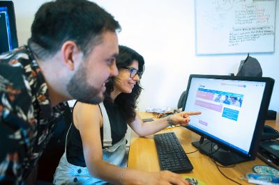 Dos personas jóvenes frente al computador, viendo el sitio de DEMRE