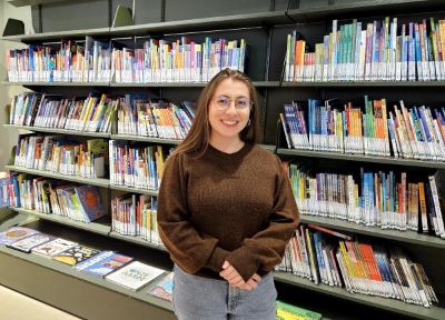 Plano americado de Teresa Paneque, de fondo una biblioteca llena de libros