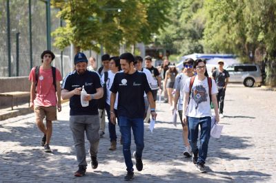 Grupo de estudiantes junto a monitores, caminando al aire libre, al interior de la Facultad de Economía y Negocios de la Universidad de Chile