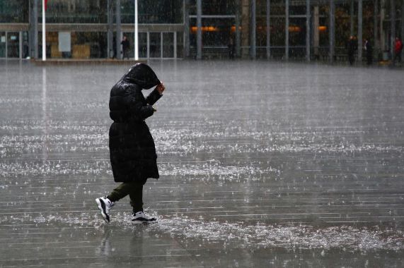 La imagen muestra a una persona caminando bajo la lluvia.