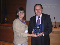 Dr. Fernando Gallardo recibe su reconocimiento de manos de la Dra. María Angélica Torres.