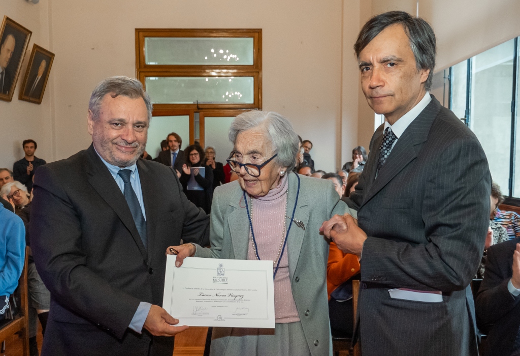 El Decano Pablo Ruiz-Tagle entregando la medalla "Premio Facultad de Derecho" la egresada Laura Novoa, quien es acompañada por su hijo, profesor Álvaro Anríquez.
